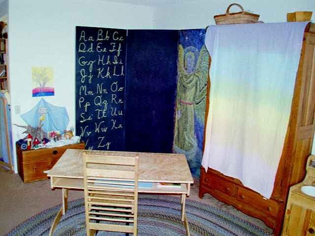 The home classroom — wooden desk, bookshelves, xylophone, and braided rug